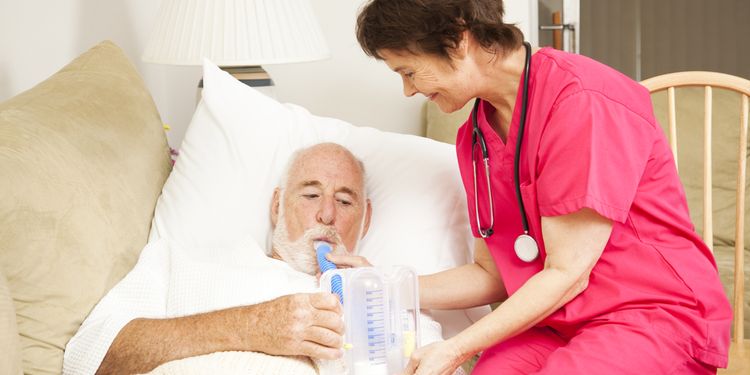 Photo of an ill old person lying in bed with nurse doing breathing test