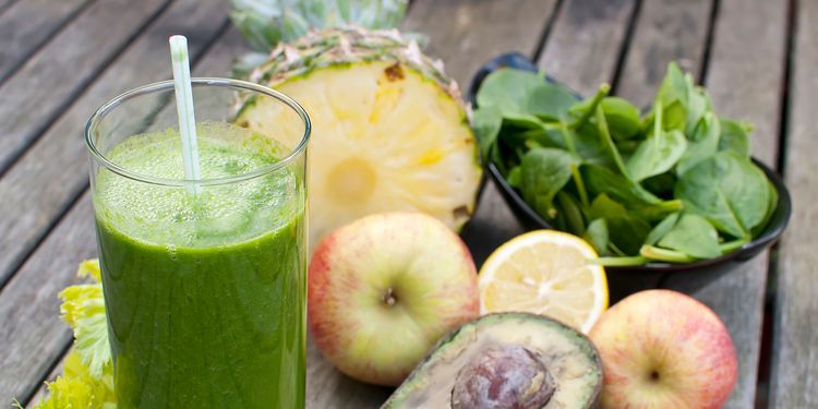 Photo of pineapple avocado green smoothie in a glass with straw