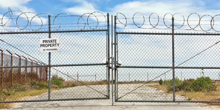 Photo of gateway with private property notice and barbed wire above