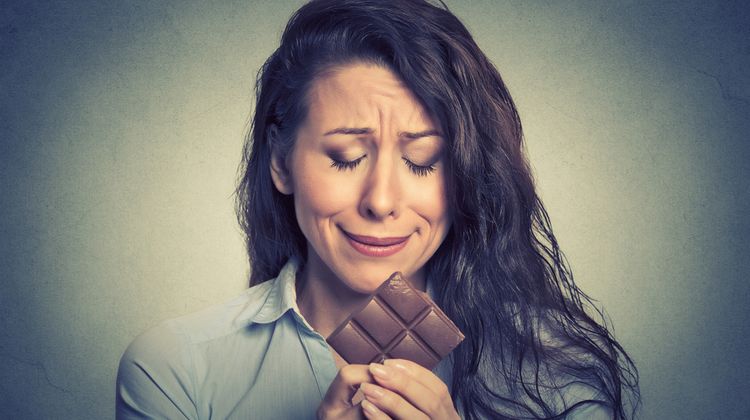 Photo of a woman with crying face looking at the block of chocolate