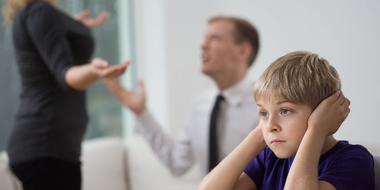 Photo of young stressed boy listening to parents argue