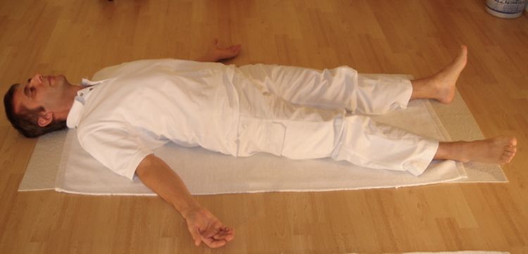 Photo of a man laying in a shavashana yoga pose