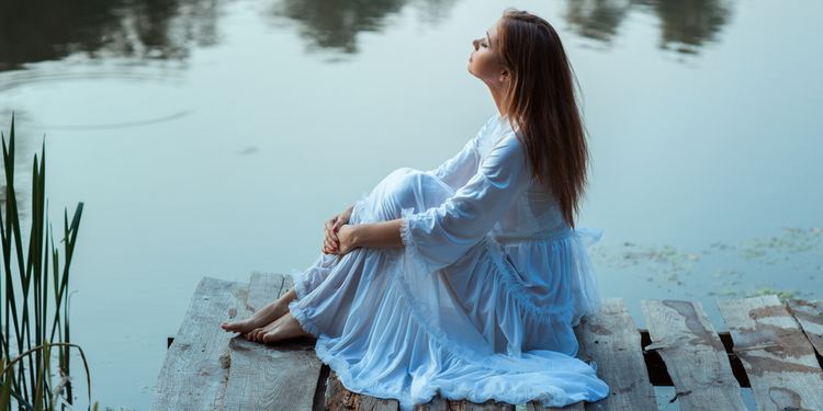 Photo of a woman sitting near river and chanting mantra