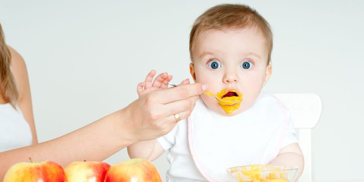 Photo of a baby spoon-fed by mother