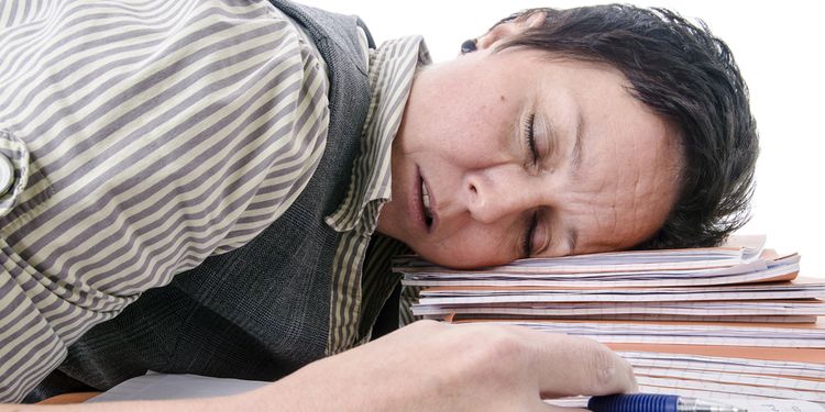 Photo of a student sleeping on a pile of books