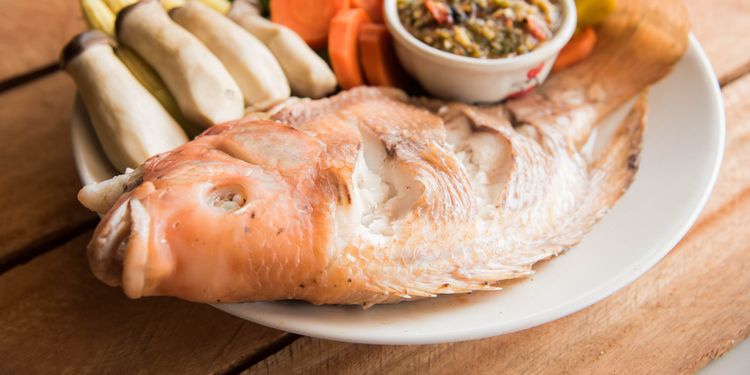 Photo of Steamed Nile tilapia fish and vegetables, served with sauce on the wooden floor