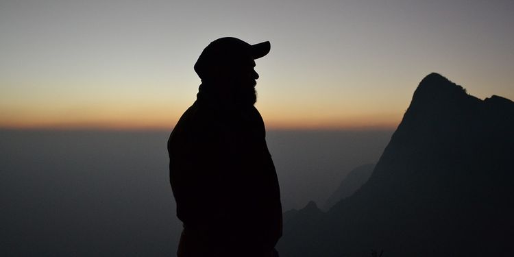 Photo of a human silhouette in sunset with mountains in background