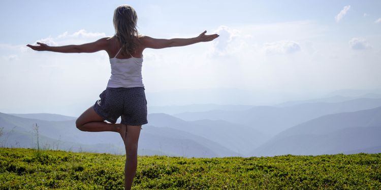 Photo of a woman meditating outdoors in tree yoga postition