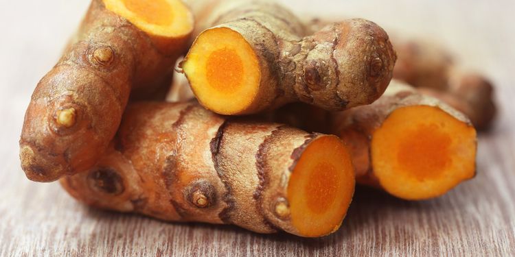 Photo close up of raw turmeric on wooden surface