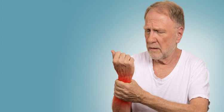 Photo of a man holding his inflamed wrist joint