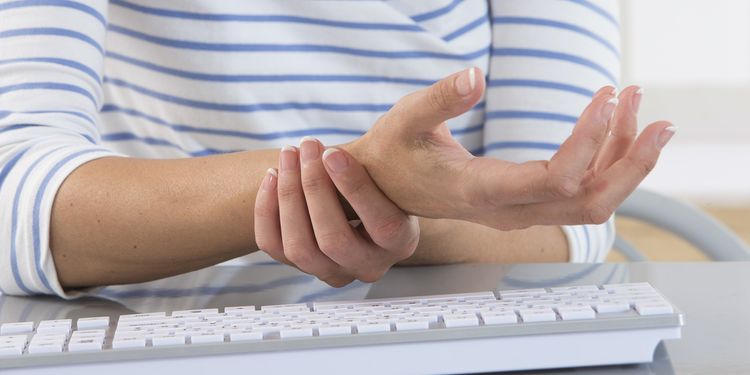 Photo of a woman holding her wrist 