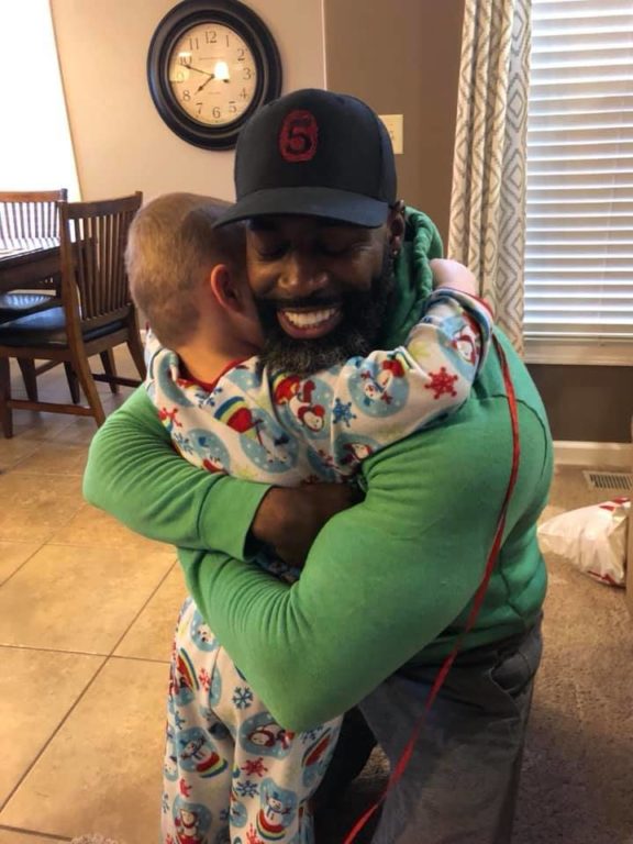 delvar in green shirt hugging kid in snowman pjs